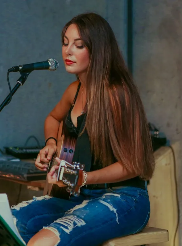 Nayeli cantando con su guitarra acústica frente al micrófono